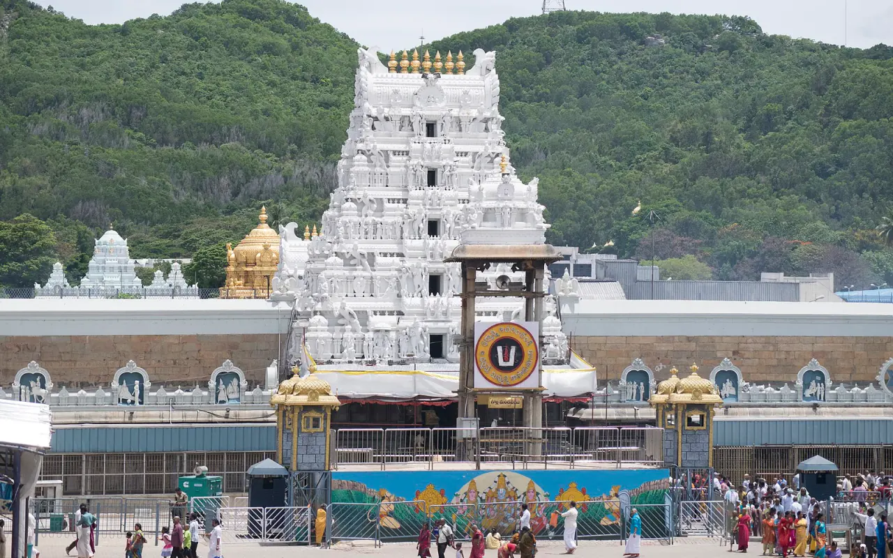 The white temple gateway at Tirumala against a wooded hillside